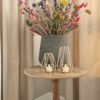 theelichtjes in een metalen houder op een tafeltje met bloemen in een pot